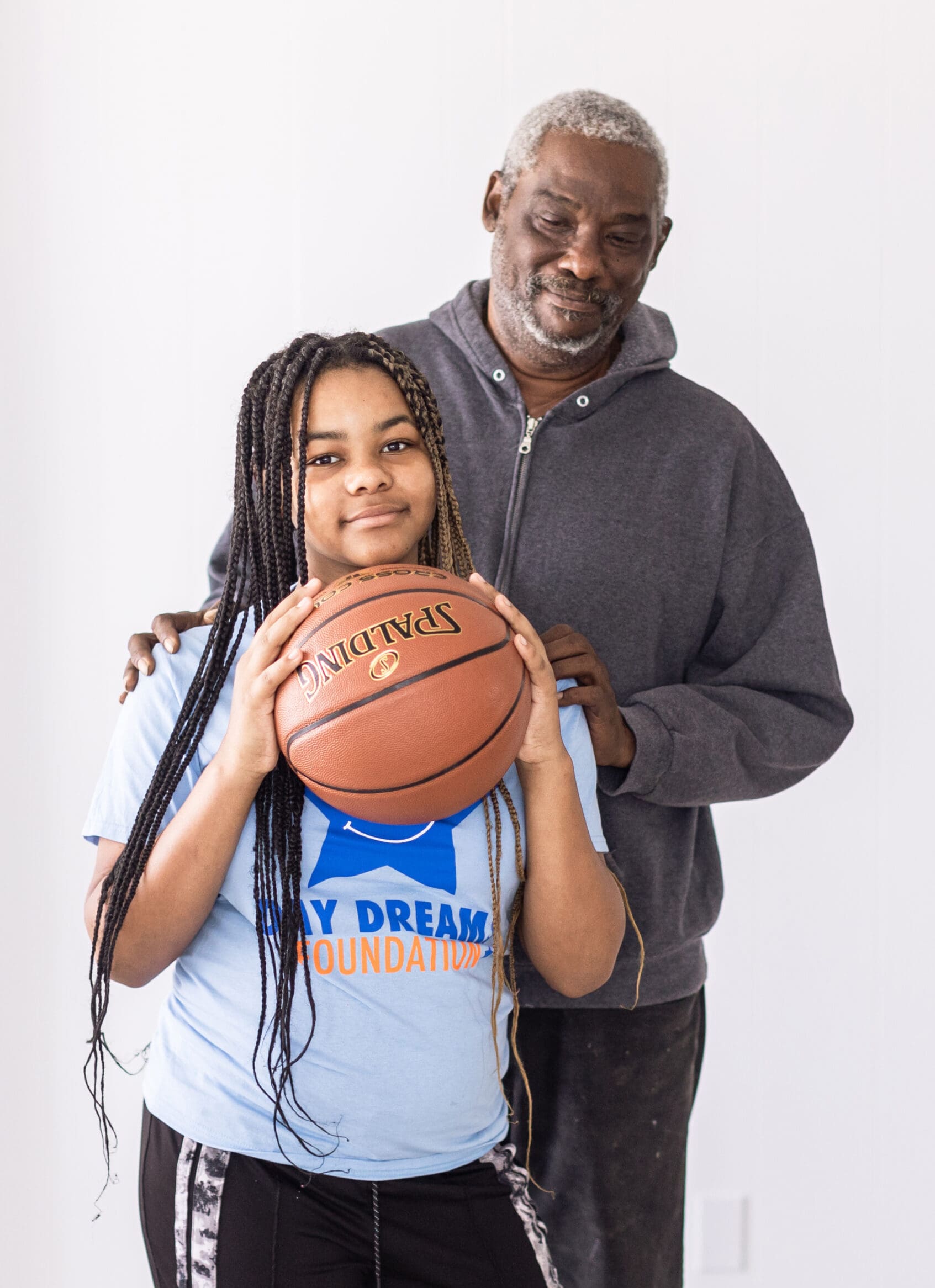 Girl with basketball with father behind her